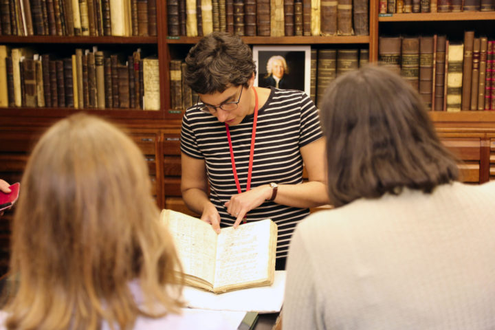 A woman shows items from the collections to visitors