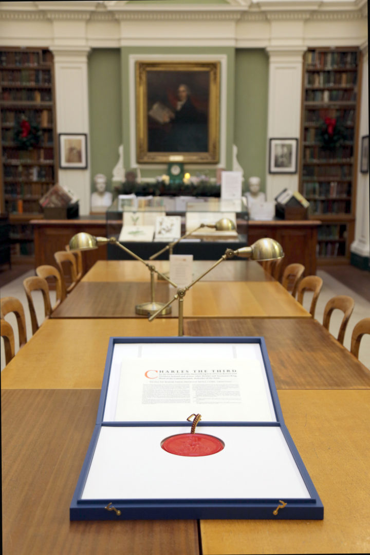 A box holding a document with an official seal lies open in a library