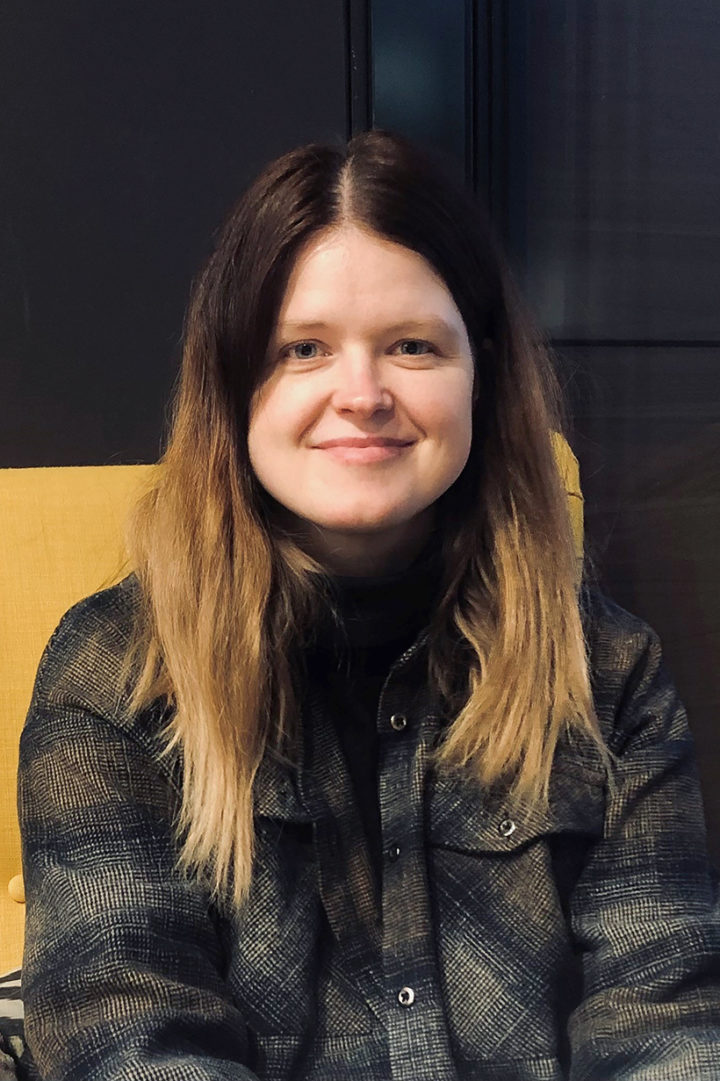 Dr Justyna J. Miszkiewicz smiles sitting on a yellow chair