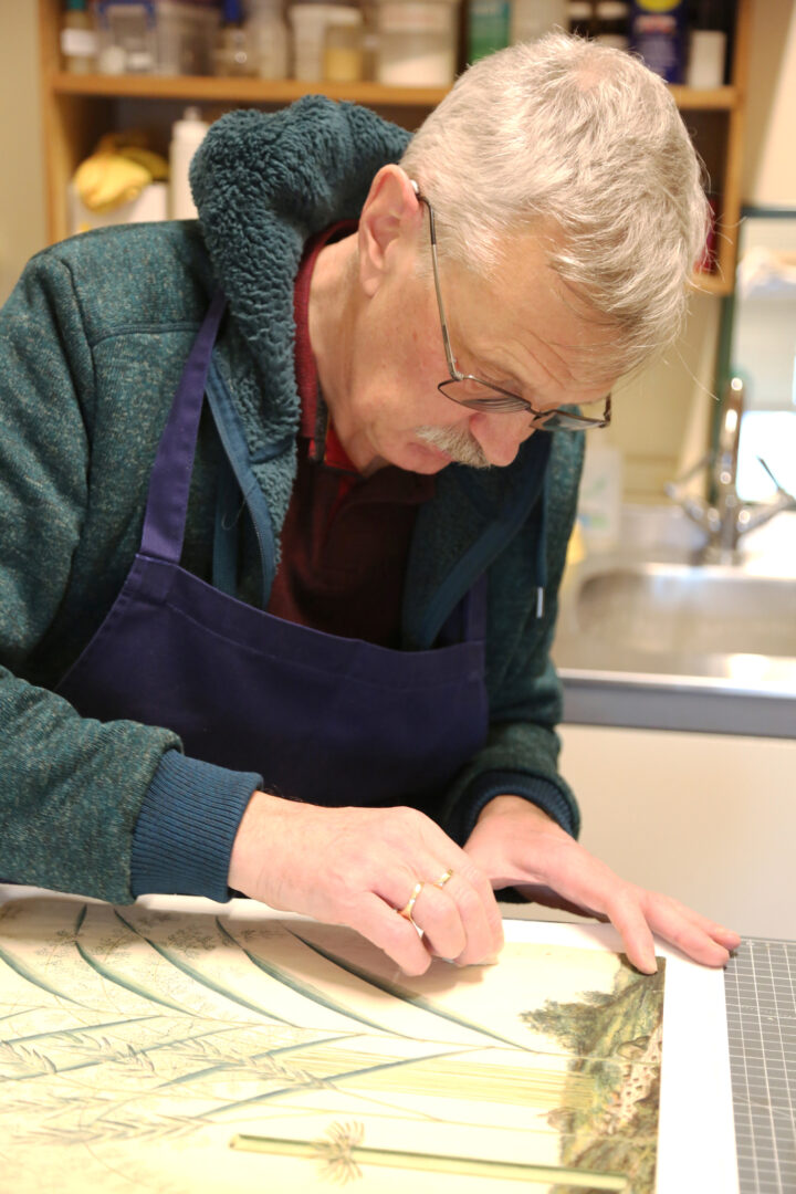 A man leant over a document, cleaning it with a smoke sponge