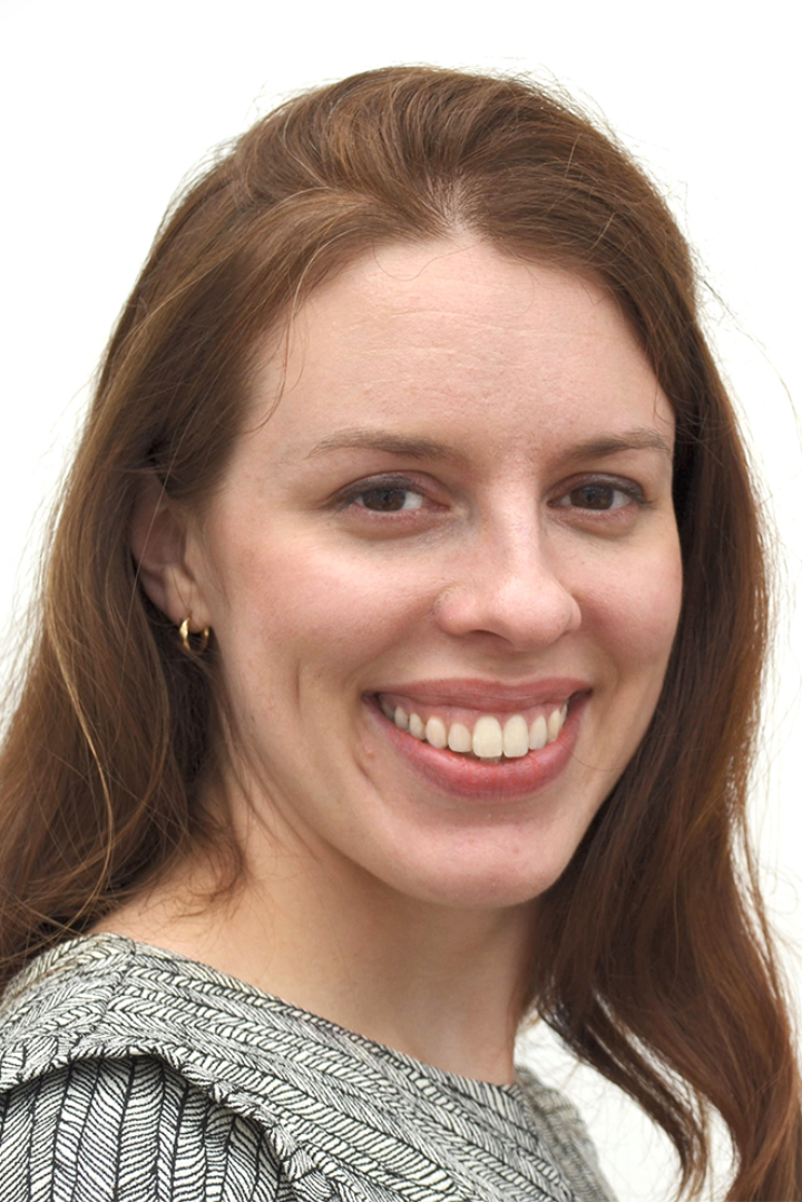 Auburn-haired woman looks at the camera smiling