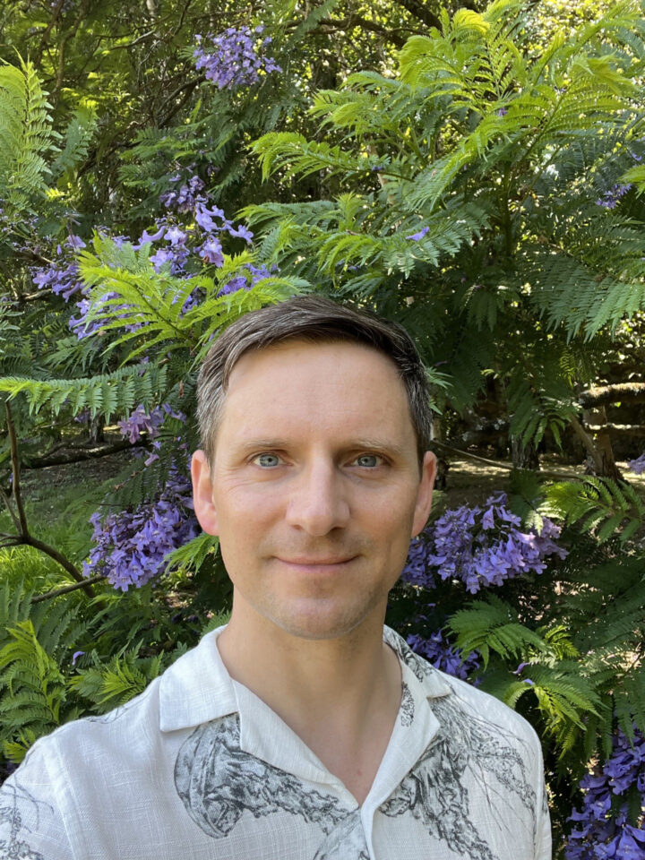 An image of man stood into front of some plants.