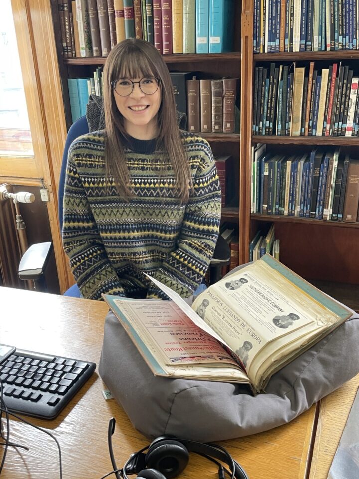 A young woman sitting at a desk, surrounded by archival material