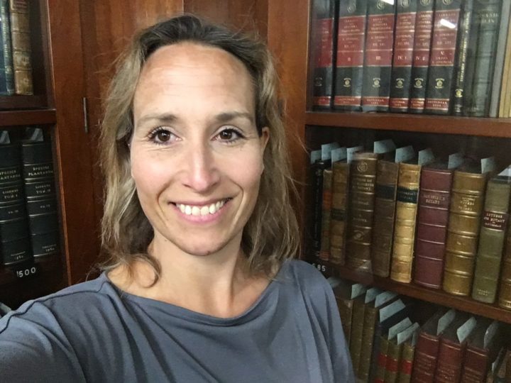 Andrea Hart smiling at camera in front of a bookshelf
