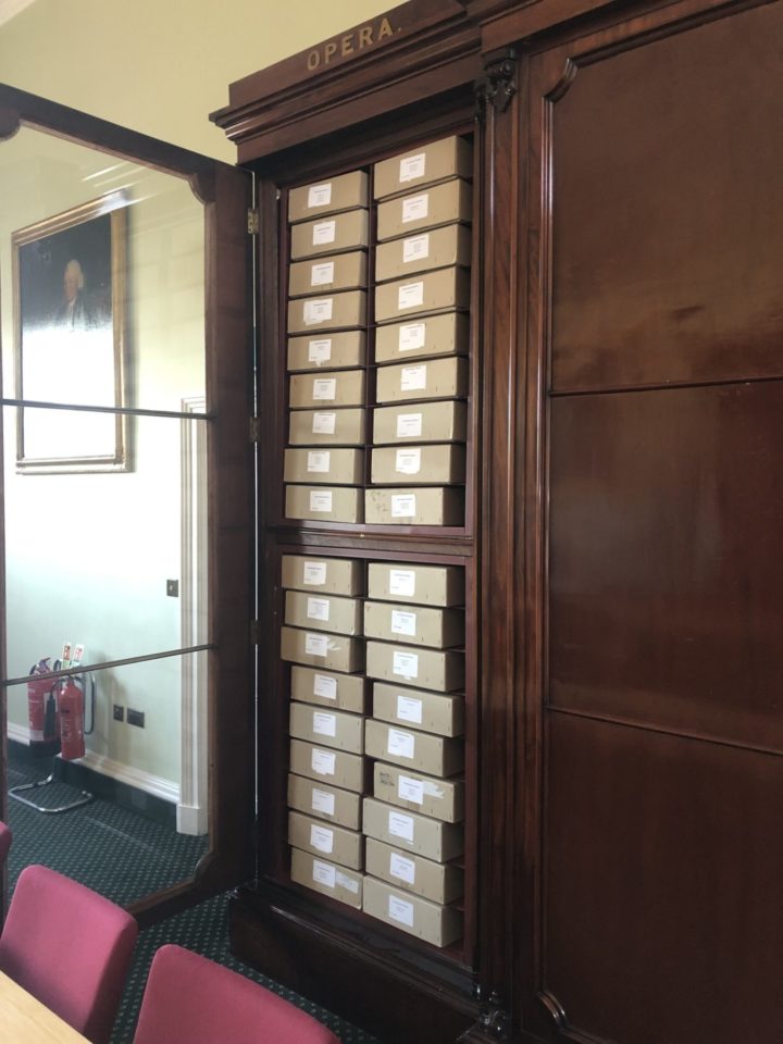a tall cupboard with brown archive boxes inside