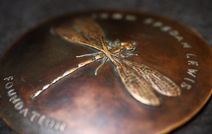 A medal shows a raised dragonfly design