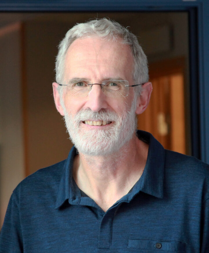 Professor Roger Butlin standing in front of a bookshelf and smiling