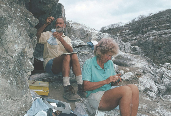 A man and a woman sit on rocks looking at scientific instruments