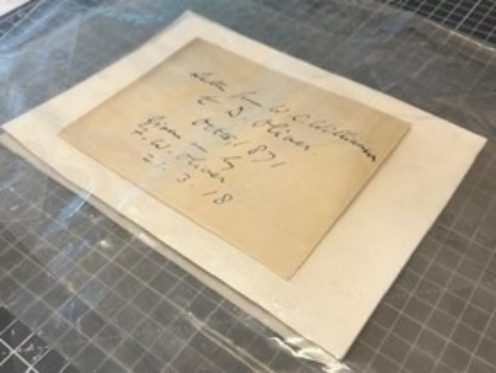 A handwritten envelope laying on a piece of blotting paper with a layer of polethene on top
